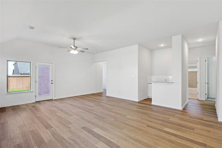 Empty room featuring lofted ceiling, ceiling fan, and light hardwood / wood-style flooring