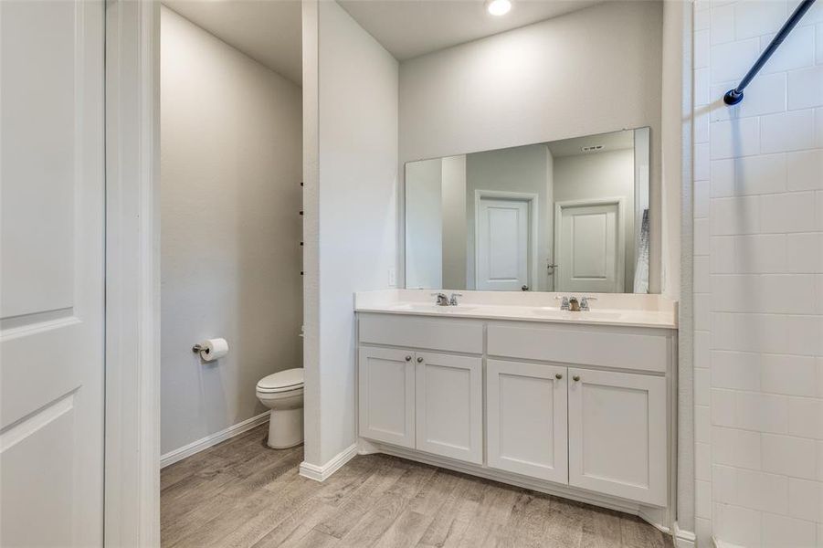 Bathroom featuring a shower with curtain, vanity, toilet, and hardwood / wood-style flooring