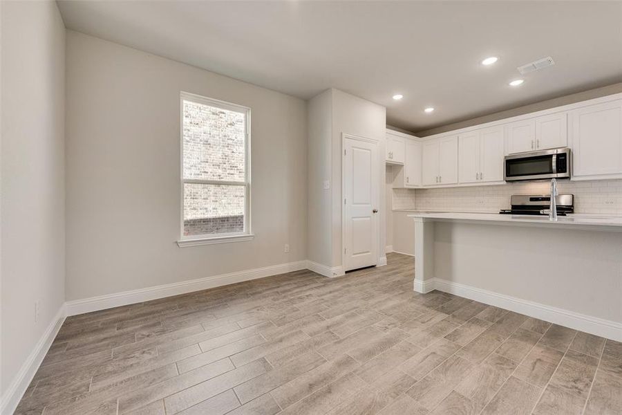 Kitchen featuring white cabinets, stainless steel appliances, backsplash, and light hardwood / wood-style floors