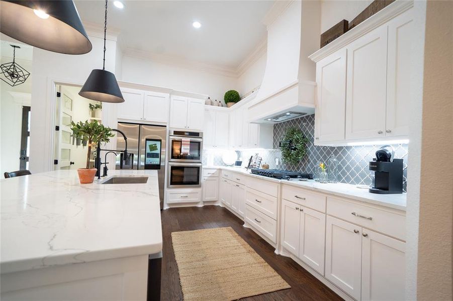 Kitchen featuring premium range hood, white cabinetry, light stone countertops, crown molding, and dark hardwood / wood-style flooring