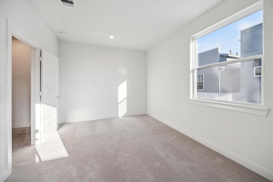 Secondary bedroom on the third floor provides ample natural light and a cozy atmosphere. With neutral tones and plush carpeting, the space offers a blank canvas for customization, whether used as a bedroom, guest room, or home office. Generous closet space and proximity to the primary bedroom makes it both functional and comfortable.