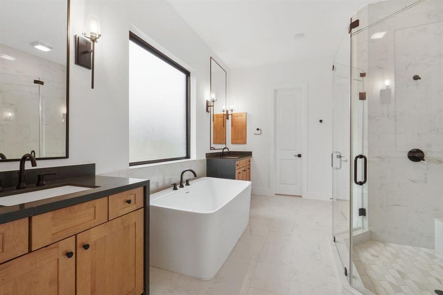 Luxurious Main bath features enlarged shower with two shower heads, soaker tub and waterfall porcelain counters adorned with elagant sconces above seperate vanties.