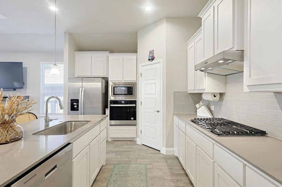 SS Appliances, Quartz Counters, large island, gas cooktop and wood look tile ceramic flooring