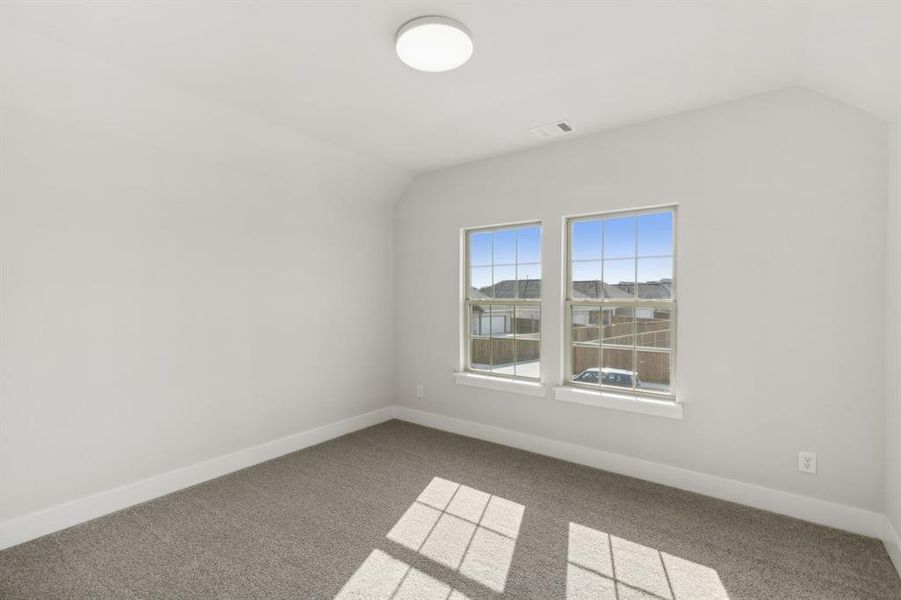 Carpeted spare room with lofted ceiling