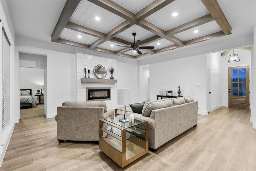 Living room with light hardwood / wood-style flooring, ceiling fan, beam ceiling, and coffered ceiling