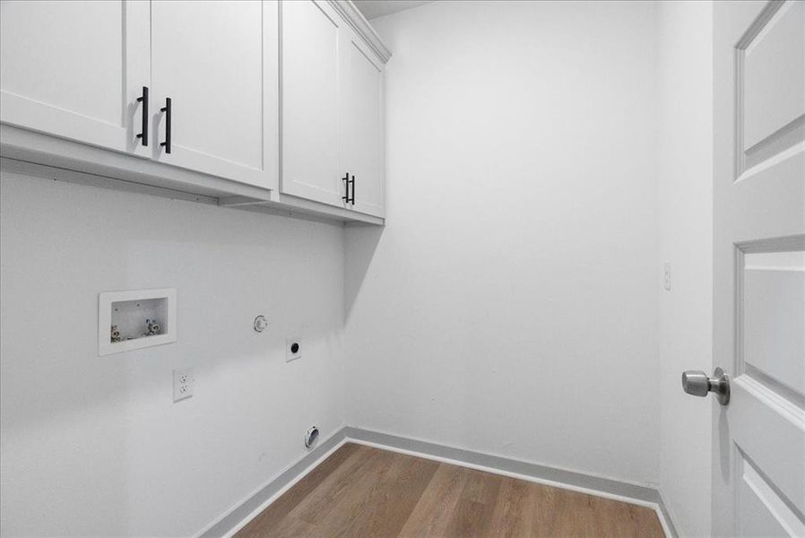 Washroom with cabinets, light hardwood / wood-style floors, washer hookup, hookup for an electric dryer, and gas dryer hookup