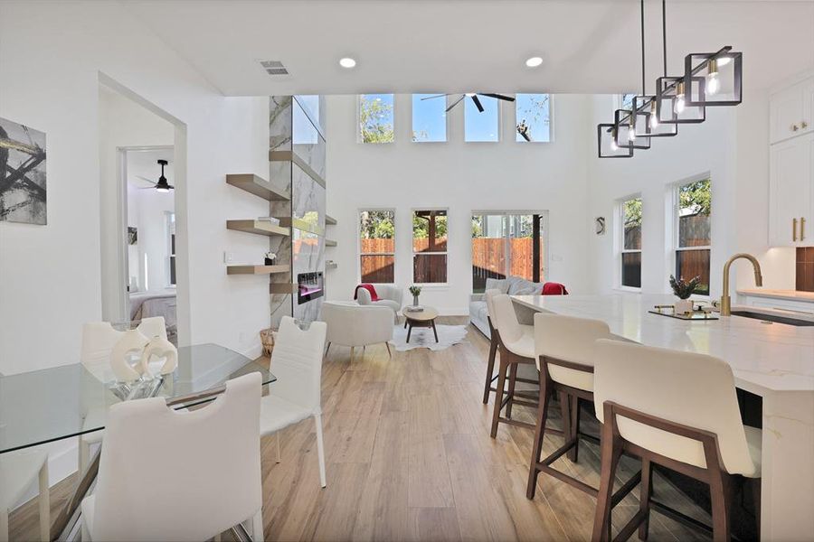 Dining area with a high ceiling, light hardwood / wood-style flooring, plenty of natural light, and sink