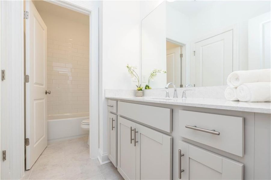 Full bathroom with tile patterned flooring, toilet, vanity, and tiled shower / bath