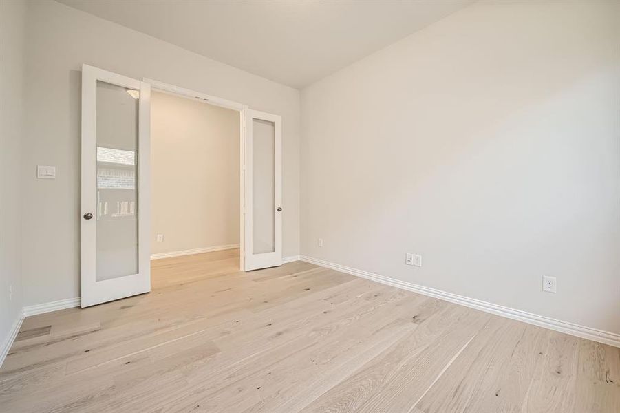 Unfurnished room featuring french doors and light hardwood / wood-style flooring