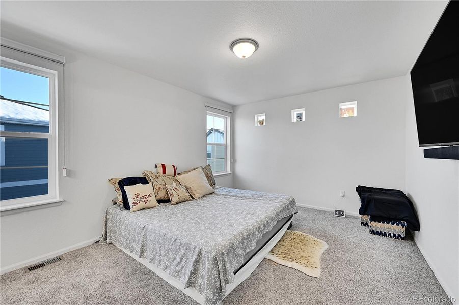 Head upstairs where you will be greeted by the primary bedroom. Enjoy the plush carpet floroing and multiple windows allowing light to shine in.