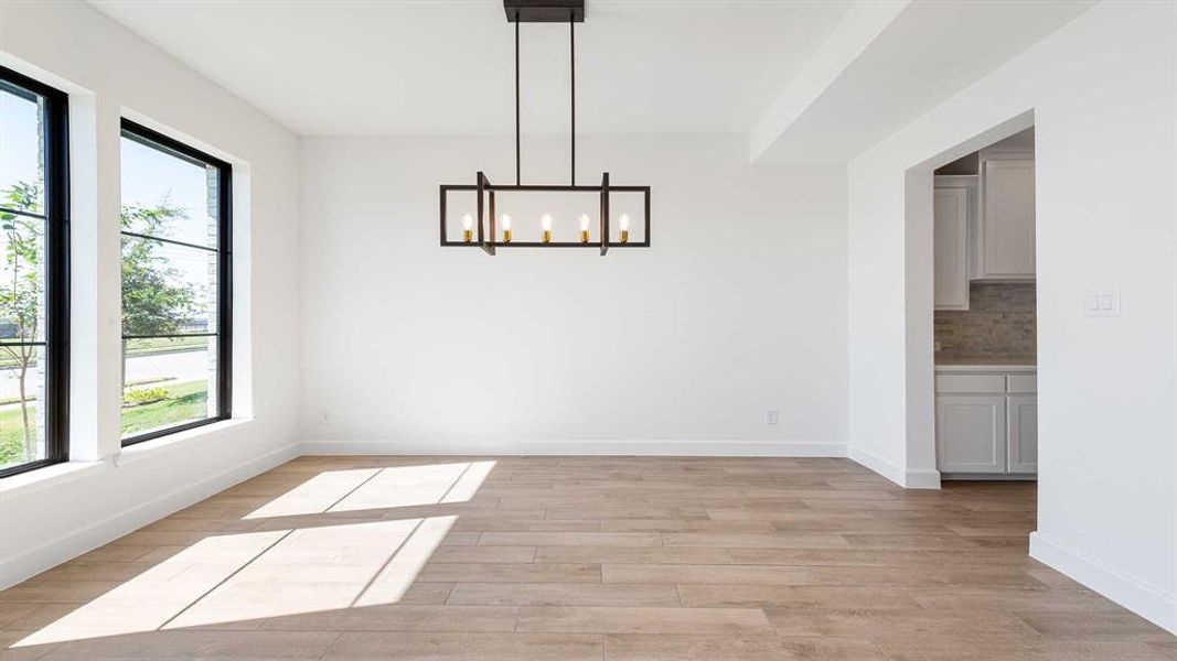 Unfurnished dining area with light hardwood / wood-style flooring, a notable chandelier, and a wealth of natural light