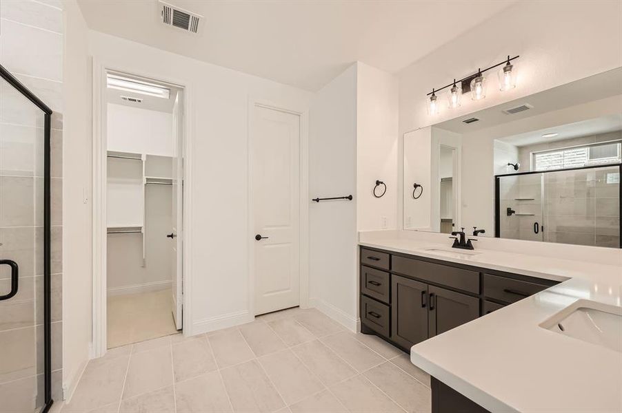 Bathroom with vanity, a shower with door, and tile patterned floors