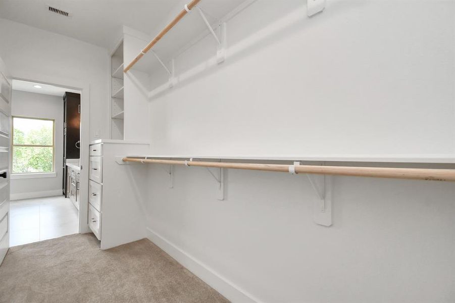 Adjacent to the primary ensuite bathroom, we see the expansive walk-in closet with built-in cabinetry and shelving!