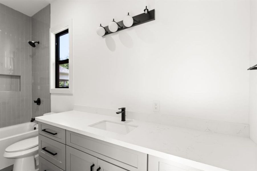 The guest quarters bathroom features a tub/shower combo with tile surround, extended quartz countertop and luxurious finishes.