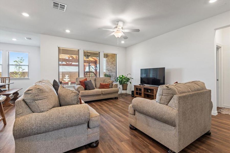 Living room featuring a healthy amount of sunlight, ceiling fan, and dark hardwood / wood-style flooring