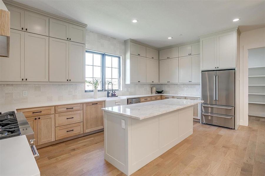 Kitchen with a center island, appliances with stainless steel finishes, decorative backsplash, and light wood-type flooring