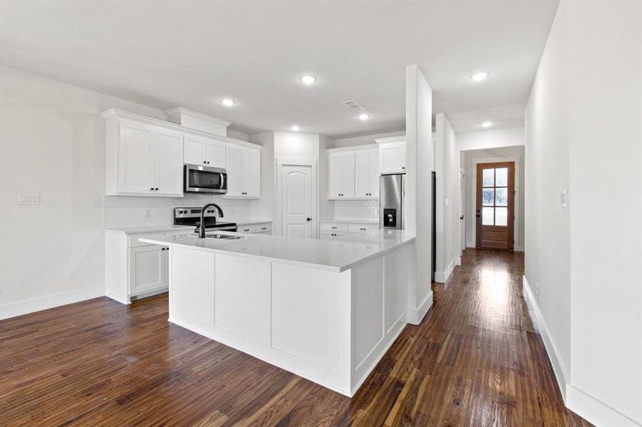 Kitchen with white cabinets, stainless steel appliances, and dark wood-type flooring