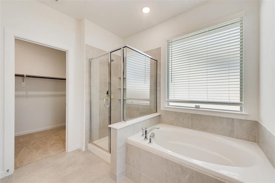 Bathroom featuring plenty of natural light, tile patterned floors, and shower with separate bathtub