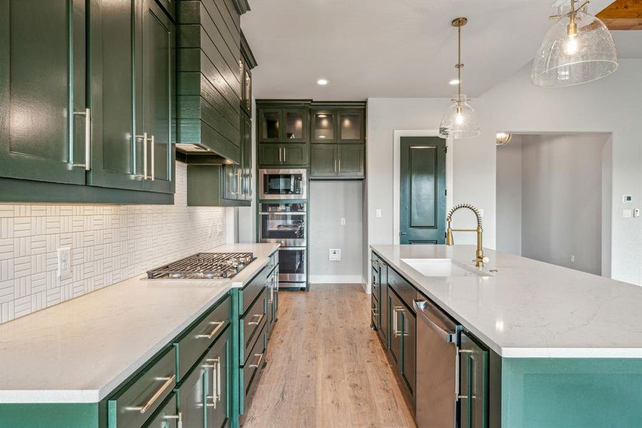 Kitchen featuring sink, light hardwood / wood-style flooring, green cabinets, and an island with sink