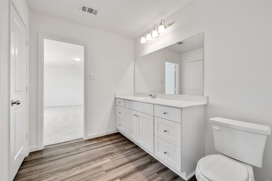 Bathroom with hardwood / wood-style floors, vanity, and toilet