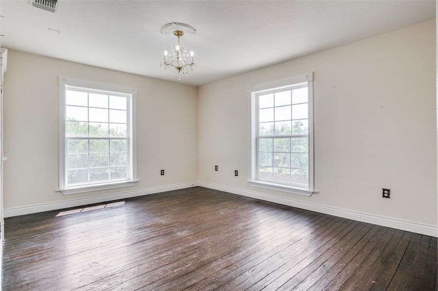 Spare room with a wealth of natural light and dark wood-type flooring