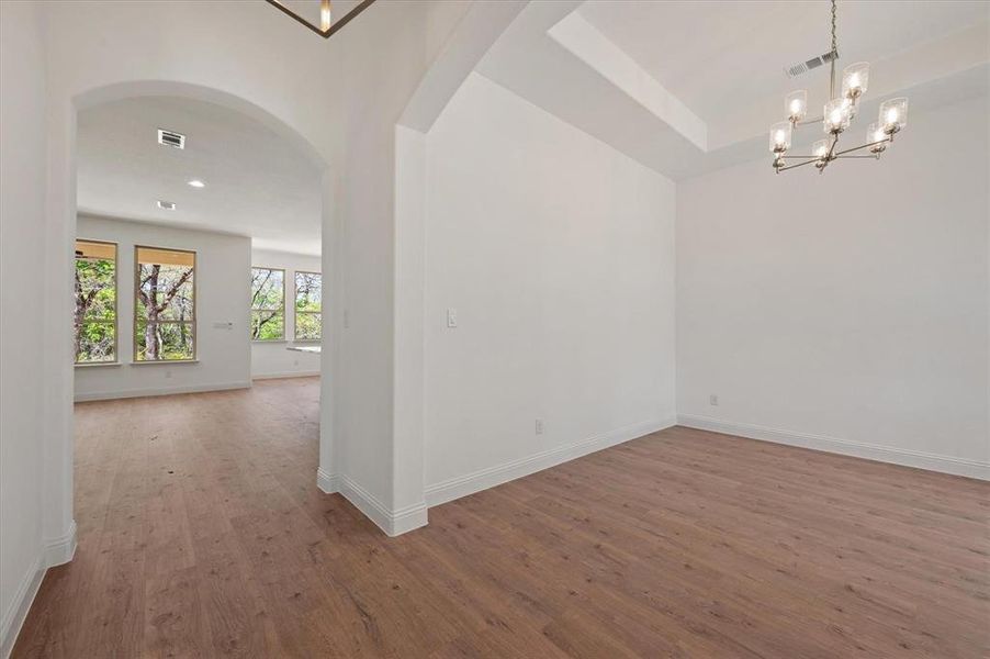 Empty room with wood-type flooring and a chandelier