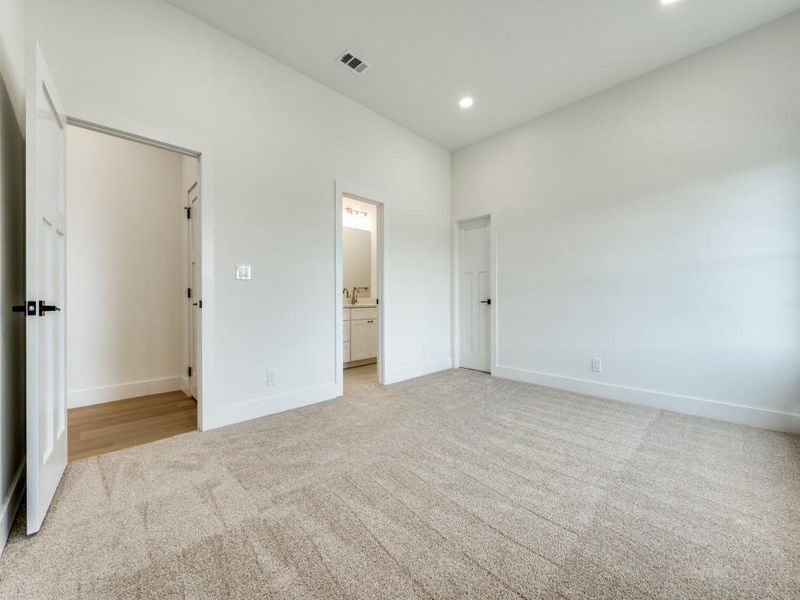 Unfurnished bedroom featuring ensuite bath and light colored carpet