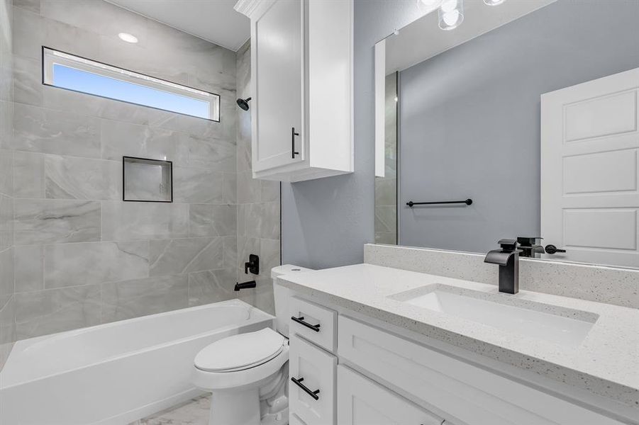 Full bathroom with tiled shower / bath, oversized vanity, and toilet