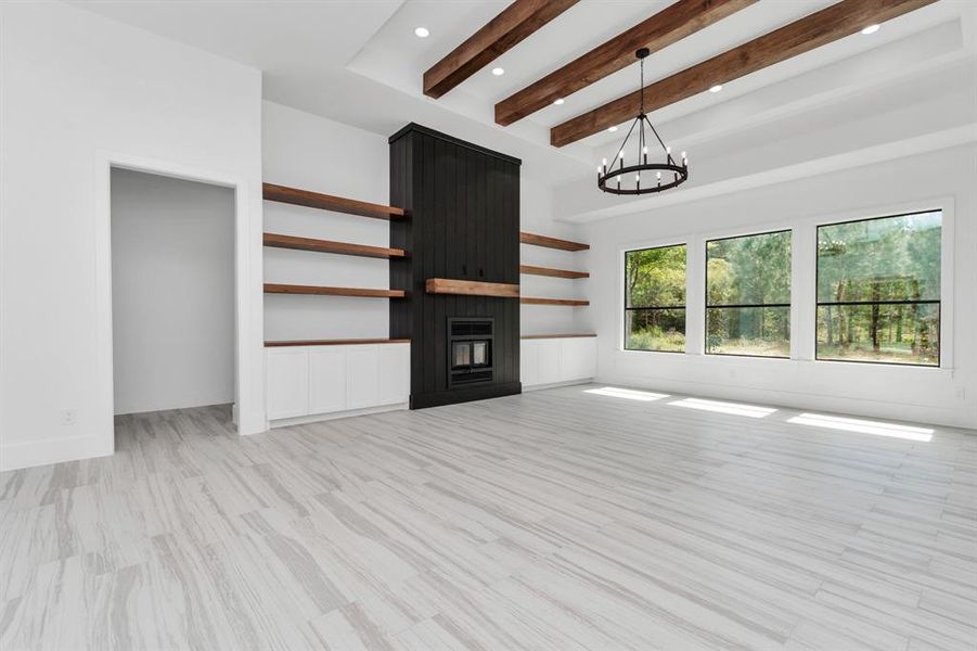 A large black built-in fireplace with floating shelves, and an abundance of natural light from floor-to-ceiling windows offering a view of greenery outside.