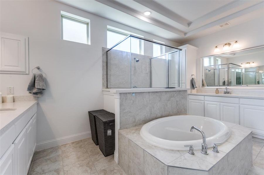 Bathroom with separate vanities, walk-in shower, garden tub, and patterned tile floors