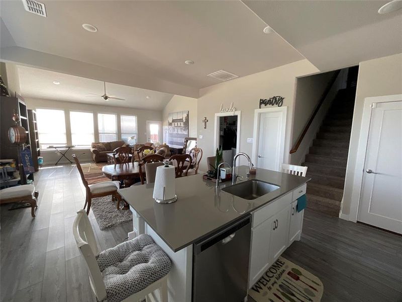 Kitchen featuring an island with sink, white cabinets, dark hardwood / wood-style flooring, dishwasher, and sink