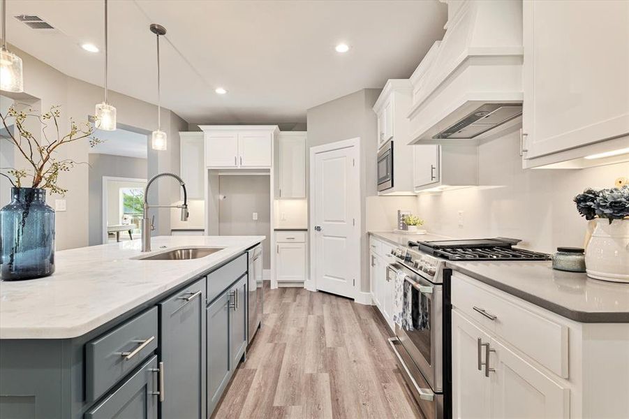 Kitchen featuring sink, appliances with stainless steel finishes, light hardwood / wood-style flooring, premium range hood, and white cabinets