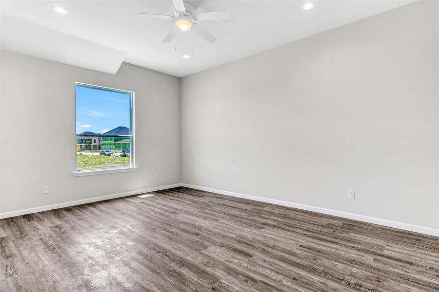 Primary bedroom with ceiling fan and hardwood / wood-style flooring