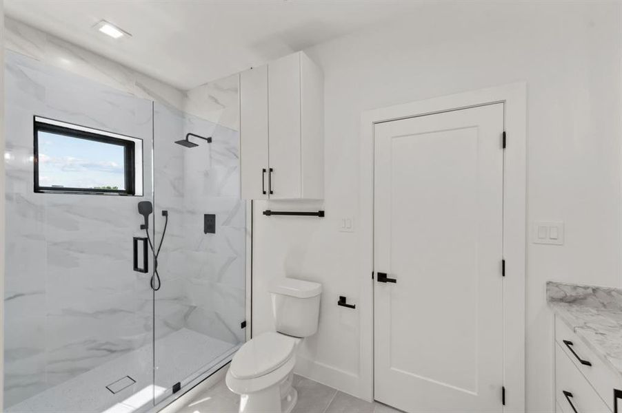 Bathroom featuring vanity, toilet, and a shower with shower door