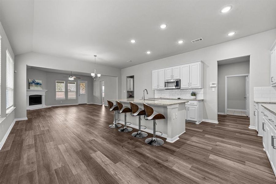 Kitchen with white cabinetry, sink, dark wood-type flooring, a kitchen breakfast bar, and a kitchen island with sink