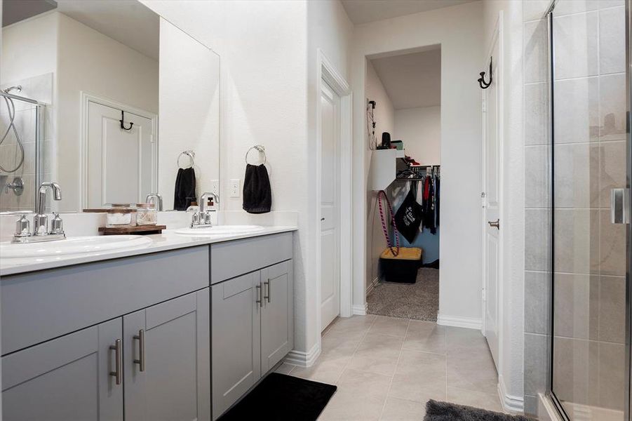 Bathroom with double sink vanity, walk in shower, and tile patterned flooring