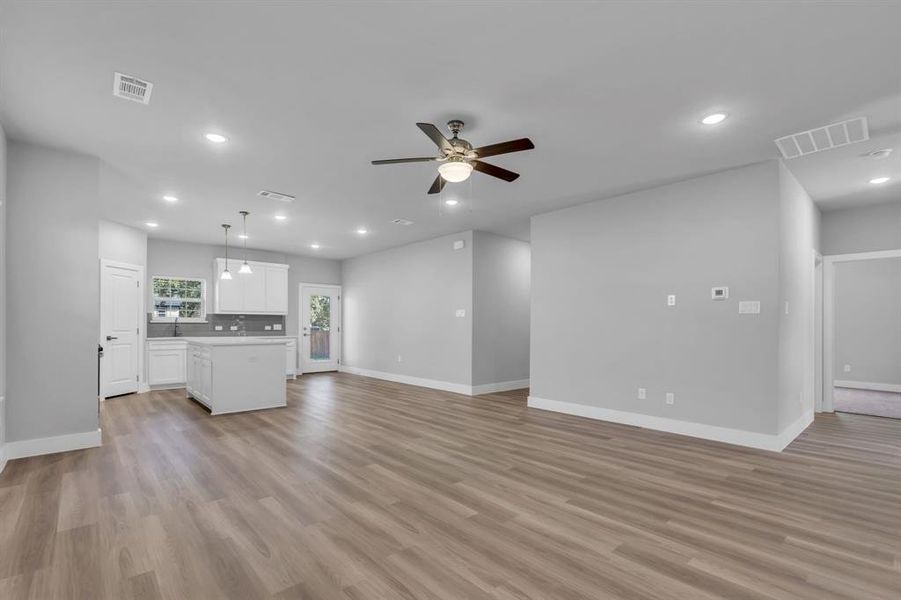 Unfurnished living room with light wood-type flooring and ceiling fan