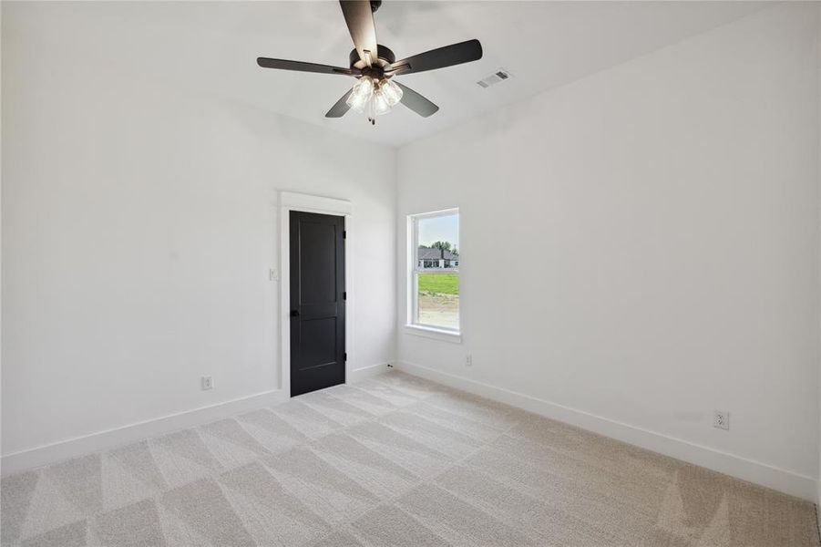 Empty room featuring light colored carpet and ceiling fan