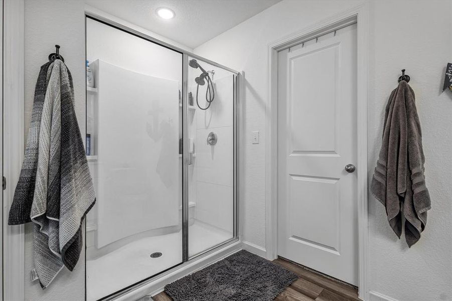 Bathroom featuring a shower with shower door and hardwood / wood-style flooring