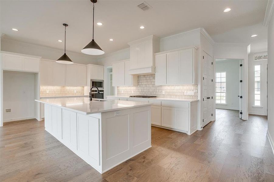 Kitchen with a kitchen island with sink, sink, white cabinetry, light hardwood / wood-style flooring, and appliances with stainless steel finishes