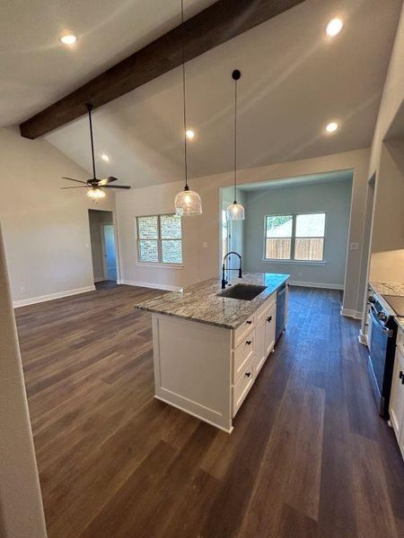 Kitchen featuring lofted ceiling with beams, sink, white cabinets, a center island with sink, and dark hardwood / wood-style flooring