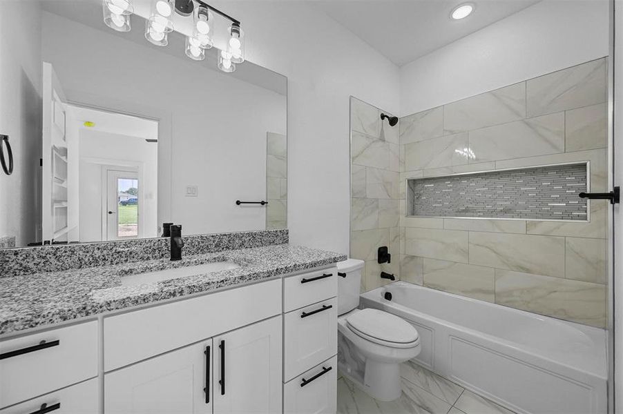 Full bathroom with tile patterned floors, vanity, tiled shower / bath, and toilet