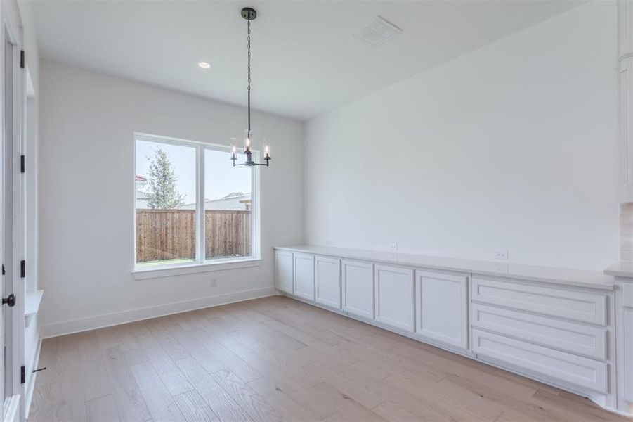 Unfurnished dining area featuring an inviting chandelier and light wood-type flooring