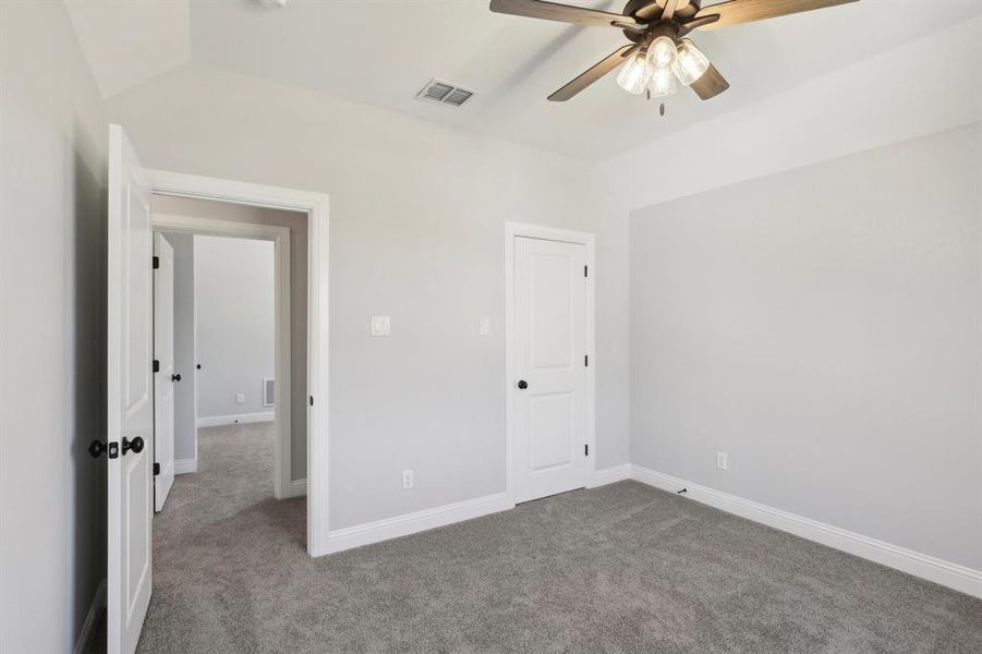 Unfurnished bedroom with lofted ceiling, carpet floors, and ceiling fan