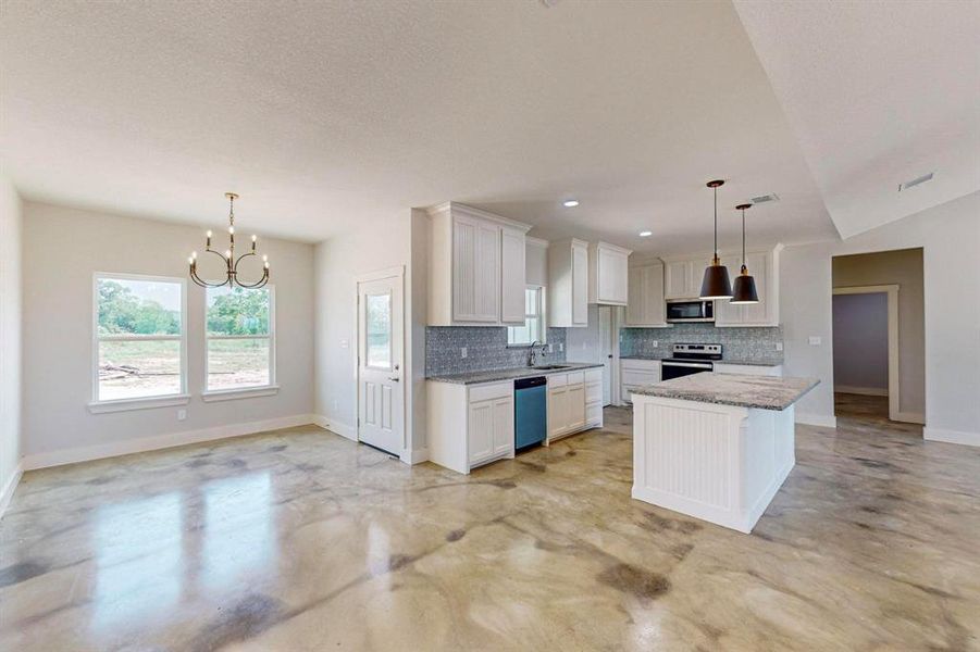 Kitchen with stainless steel appliances, white cabinets, hanging light fixtures, a kitchen island, and decorative backsplash