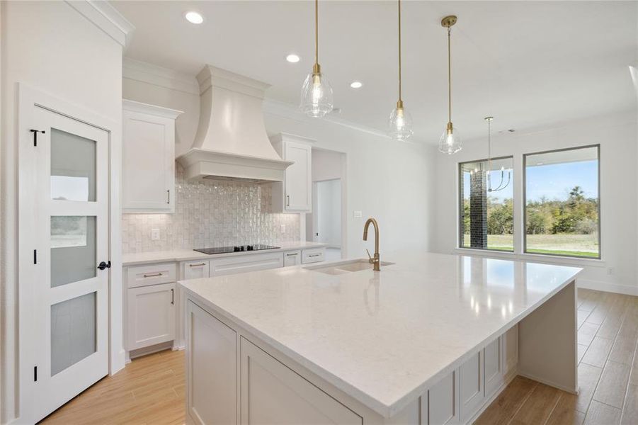 Kitchen with a large island, premium range hood, and white cabinets