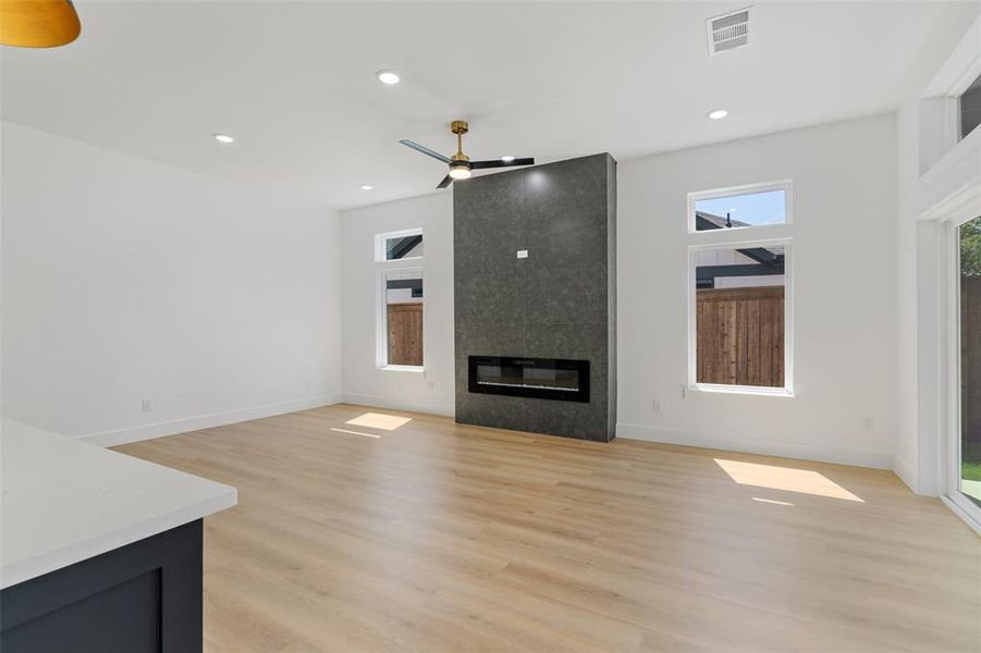 Unfurnished living room with ceiling fan, light hardwood / wood-style floors, and a large fireplace