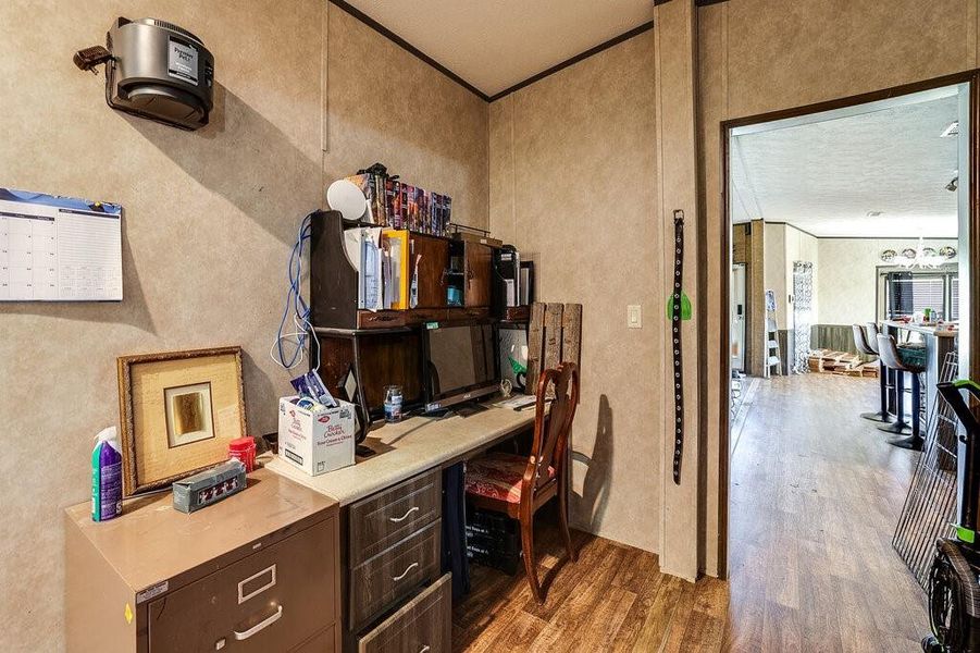 Office area featuring wood-type flooring, a textured ceiling, and ornamental molding