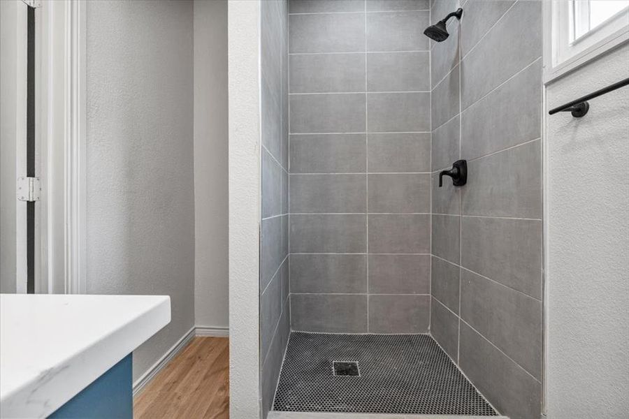 Bathroom featuring tiled shower and hardwood / wood-style floors