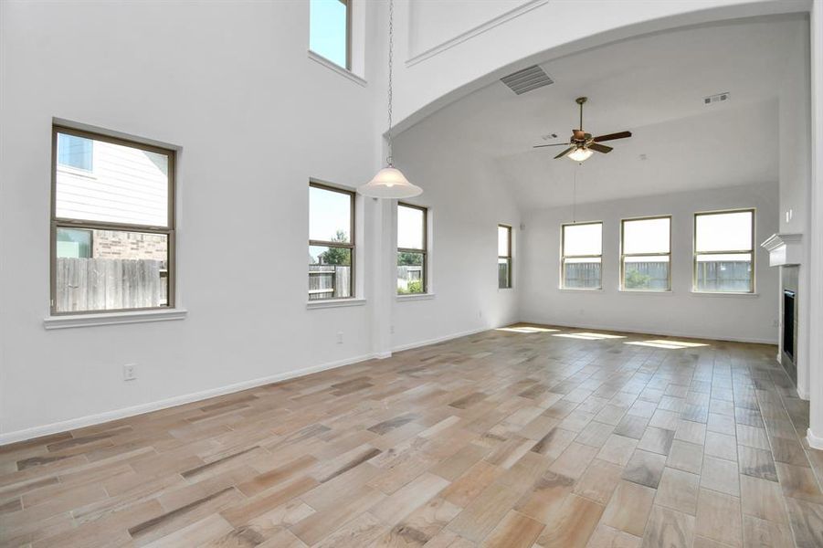 This is a spacious and bright room with high vaulted ceilings, large windows for natural light, a ceiling fan for air circulation, and a modern, light flooring.